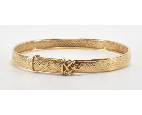A gold bangle bracelet of round expanding form with moulded celtic knot design to the exterior. Unmarked tests indicate 9ct g