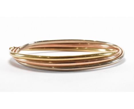 A hallmarked 9ct gold tri tone bangle bracelet. The bracelet of crossover form having a tongue in groove clasp. Import marked