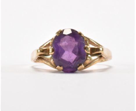 A hallmarked 9ct gold and purple stone dress ring. The ring being set with an oval cut purple stone on split shoulders. Hallm