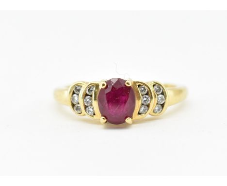 A hallmarked 18ct yellow gold ruby and diamond ring. The ring set with a central oval cut ruby flanked by tiered crescent set