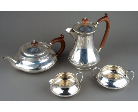 A George V silver four piece tea service comprising teapot, sugar bowl, milk jug and hotwater jug, plain squab bodies with be
