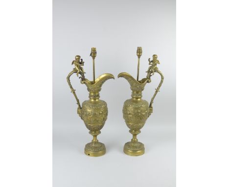 A large pair of ornate brass Ewer Lamps with winged cherubs to the handles, and decorated frieze of cherubs playing, 2ft 1in 
