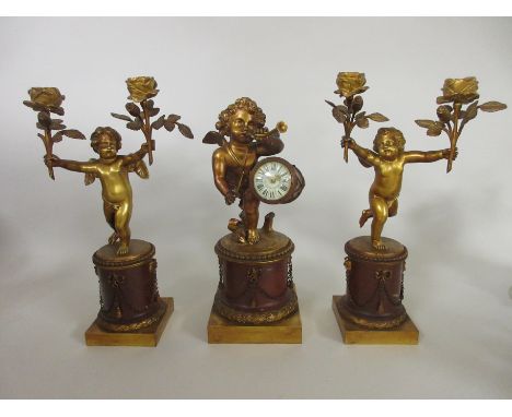 A 19th Century French Clock Garniture, the clock with drum dial supported by cherub playing pipes on circular rouge griotte b