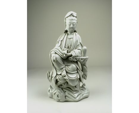 A large Chinese blanc de chine Figure of Guanyin, late Qing Dynasty or later, seated on a rock resting her arm beside a meipi