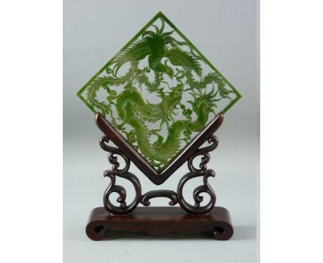 A CARVED GREEN JADE TABLE SCREEN on wooden stand, the pierced panel depicting a dragon and phoenix bird, the stand with pierc