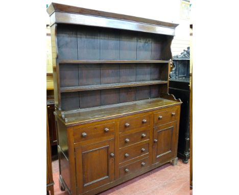 A 19th CENTURY WELSH OAK DRESSER, the shaped sided two shelf rack with wide backboards over a panel sided base with a 'T' arr