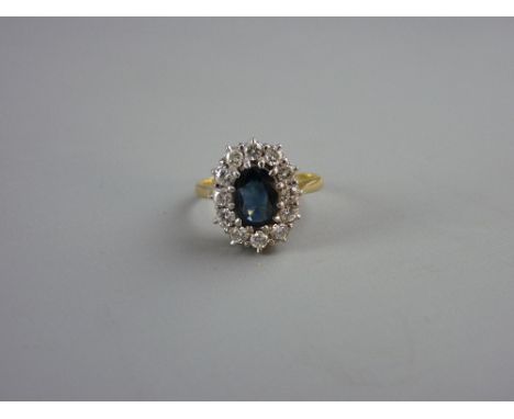 AN EIGHTEEN CARAT GOLD OVAL DRESS RING having a centre oval smoky sapphire with twelve surrounding diamonds, visual estimate 