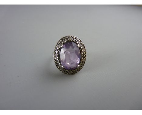 A SILVER DRESS RING with a large oval purple quartz with surrounding tiny marcasites, 6 grms total