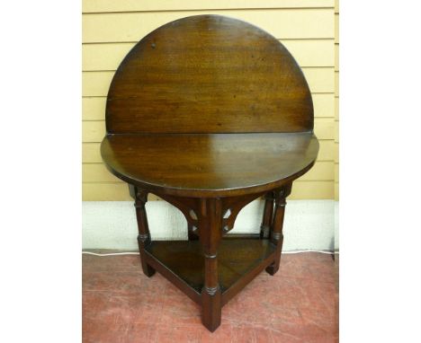 A POLISHED CIRCULAR TOPPED FOLDOVER GATE LEG SIDE TABLE with a triangular base shelf having turned supports