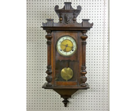 A CIRCA 1900 VIENNA STYLE WALL CLOCK with shaped mask decorated top above a single glazed door having half cut pillar decorat