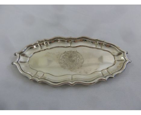 A George II silver pin tray of oval form with raised scroll border and centrally engraved coat of arms, London 1740