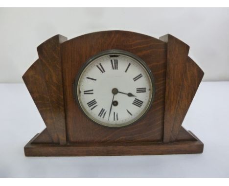 An Art Deco oak mantle clock with enamel dial and Roman numerals, single train movement