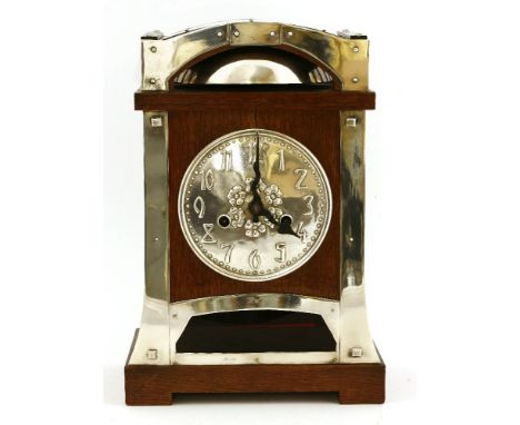 A Continental oak and silver-plated mantel clock,the embossed dial with Arabic numerals, over a glass panel,22.5cm wide16.5cm
