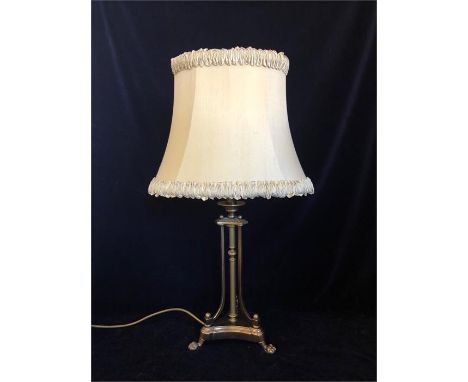 A brass table lamp on three feet