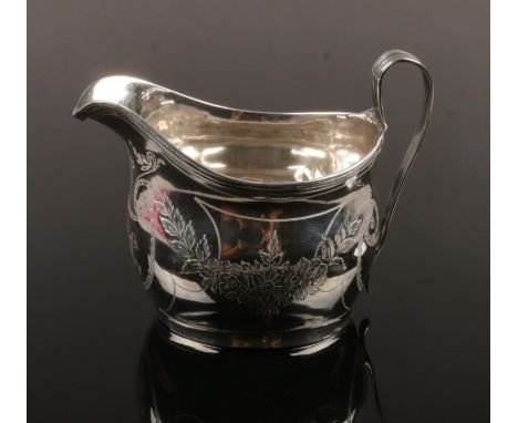 A George III silver cream jug. With reeded strap handle and engraved with festoons. Assayed London 1811, makers mark indistin