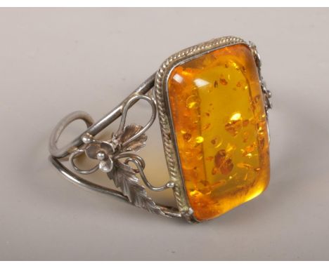 A silver bracelet with large amber effect panel.  