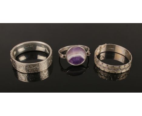 Three silver bangles, one set with an amethyst roundel plaque.  