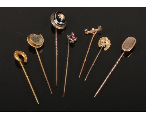 Seven antique yellow metal stick pins with assorted terminals. Including ammonite fossil, banded agate and pearl, diamond and