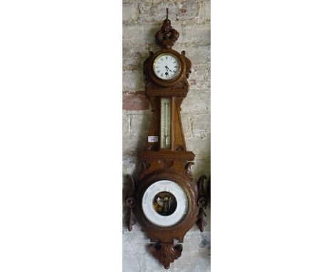 An aneroid Barometer with Barometer and time piece in a carved oak banjo pattern case. 