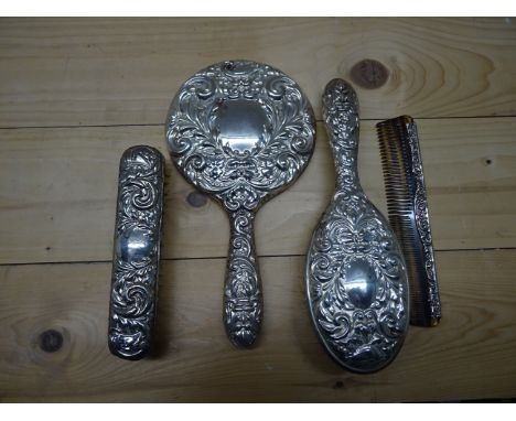 An embossed silver backed three piece Dressing Table Set, Birmingham, 1967 and similar comb, 1969.