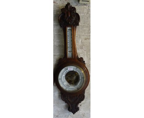 An aneroid Barometer and Thermometer in a carved oak banjo pattern case. 
