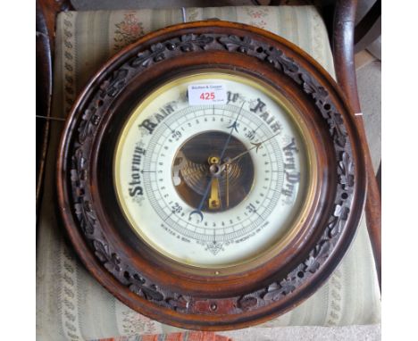 An Aneroid Barometer, the white dial inscribed 'Winter & Son, Newcastle on Tyne' in leaf carved circular case.  13" (33cms) d