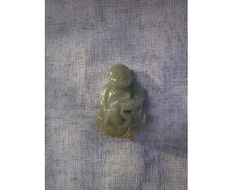 A CHINESE CARVED JADE FIGURE of a seated boy holding a cart, 3.75" high