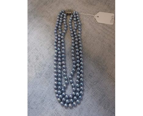 A TRIPLE STRAND SIMULATED GREY TONE PEARL NECKLACE, terminating on to a white paste cluster clasp