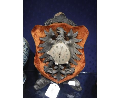 AN AUSTRIAN MANTEL TIMEPIECE, the steel dial mounted on a carved wood eagle with wings spread on a velvet shield supported by