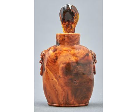 A Chinese amber snuff bottle, 20th c, carved with mask and ring handles, 75mm h, amber tear shaped stopper  Good condition