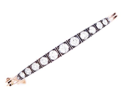 An Edwardian diamond bangle, c1910, with graduated line of eleven old cut diamonds, in gold, 61mm, 12.7g  Good condition, sto