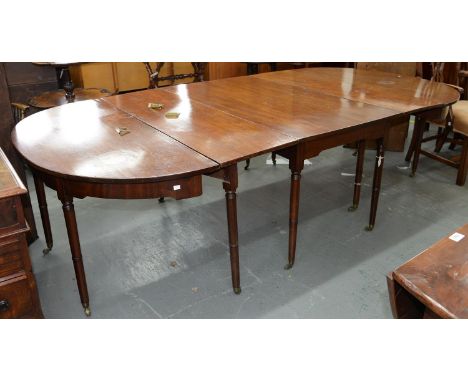 A George IV mahogany dining table, early 19th c, on twelve slender ring turned tapering legs and brass castors, each end with