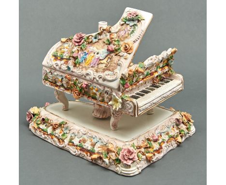 An Italian pottery floral encrusted table lamp in the form of a grand piano, c1970s,&nbsp; the case relief moulded with scene