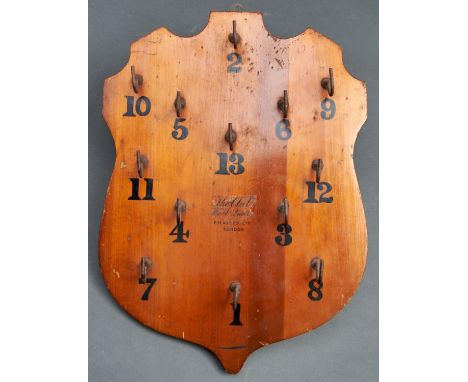 A shield shaped and varnished light wood wall quoites board, "The Club", by F H Ayres Limited London, early 20th c, with blac