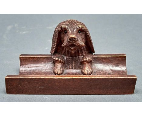A Swiss carved and stained limewood dog's head novelty inkwell and pen rest, c1900, with black boot button eyes, 18cm l  A ch