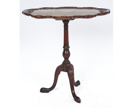 A carved mahogany tripod table, early 20th c, the shaped oval top with festoons hanging from c scrolls, on baluster knopped p