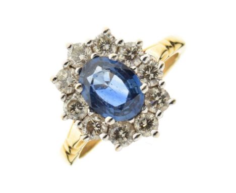 Sapphire and diamond cluster ring, stamped '750', the oval cut sapphire enclosed by ten brilliant cuts totalling approx 0.8 c