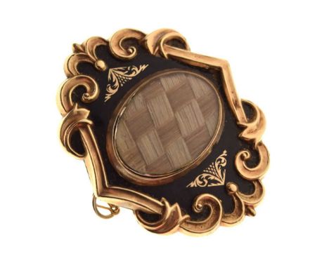 Victorian mourning brooch, the glazed oval hair panel flanked by black enamel with gilt detail, to a scroll border, the locke