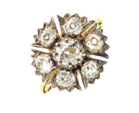 Seven-stone diamond cluster ring, stamped '18', the central silver collet set old brilliant cut enclosed by six old brilliant