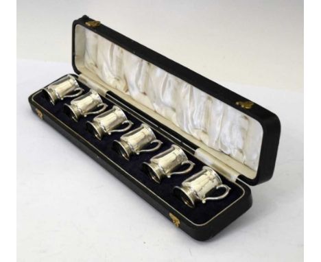 Cased set of six George V silver tot measures in the form of miniature mugs with scroll handles, sponsers mark of E.S.Barnsle