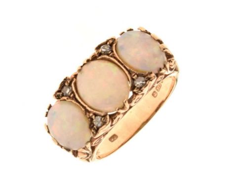 9ct gold three stone opal ring, in the Victorian carved head style, London 1975, the graduated opals with pairs of single cut