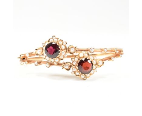 A 19th century Victorian pearl and garnet cluster bangle. The bangle having an openwork knife bar body with two garnet and pe