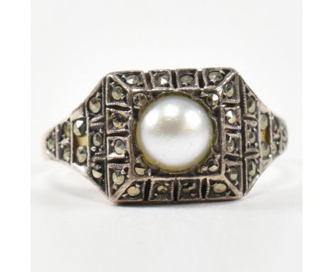 A 9ct gold, pearl and marcasite ring. The Art Deco style ring having a central pearl set in a marcasite set mount to marcasit