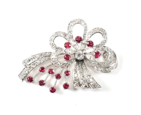 An Art Deco white gold ruby and diamond white spray brooch pin. The brooch set with a central round brilliant cut diamond to 