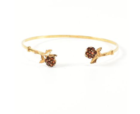 A hallmarked 9ct gold and garnet flower cluster torque bangle. The 9ct gold torque bangle set with flower shaped clusters com