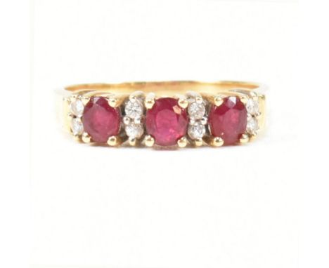 A hallmarked 18ct gold ruby and diamond three stone ring. The ring having three button prong set oval cut rubies interspersed