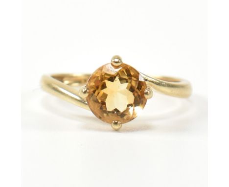 A hallmarked 9ct gold and citrine cross over ring. The ring having a compass four claw set round cut citrine in a cross over 