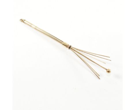 A retro hallmarked 9ct gold champagne swizzle stick fob. The vintage cocktail stirrer having an engine turned tubular form wi