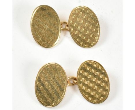A pair of hallmarked 18ct gold cufflinks. The cufflinks having oval heads with engine turned decoration united by chain.&nbsp
