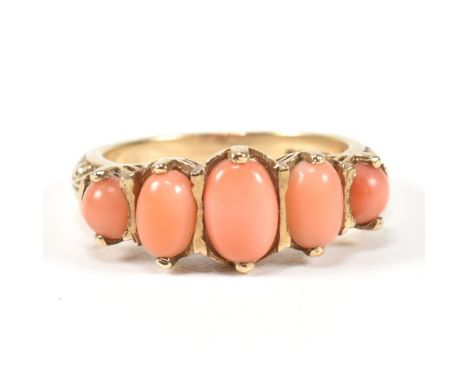 A hallmarked 9ct gold and coral five stone ring. The ring set with five oval opal cabochons to a textured mount with scroll d